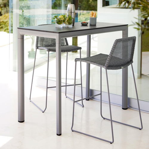 Breeze Stackable Bar Chair by Cane-Line, showing breeze stackable bar chairs with table in live shot.