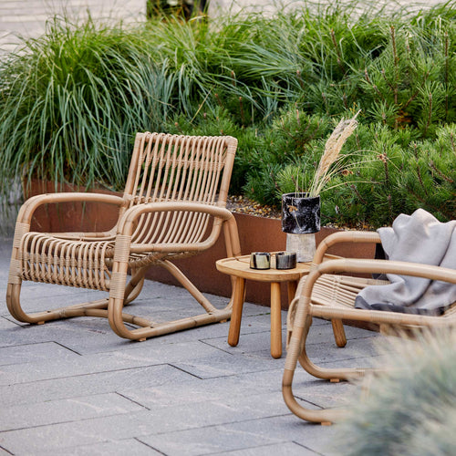 Curve Outdoor Lounge Chair by Cane-line, showing curve outdoor lounge chairs with table in live shot.