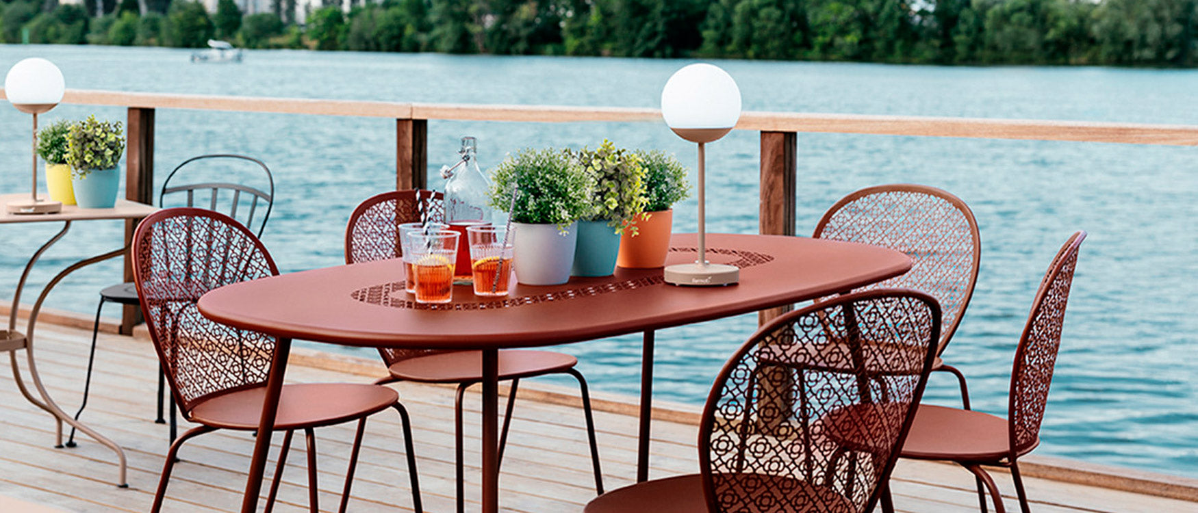 A Fermob bistro table and chairs on a deck overlooking the water