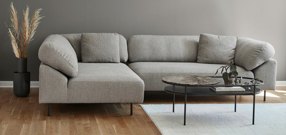 WOUD Collar open-end sectional sofa in grey with a round marble coffee table in a modern living room