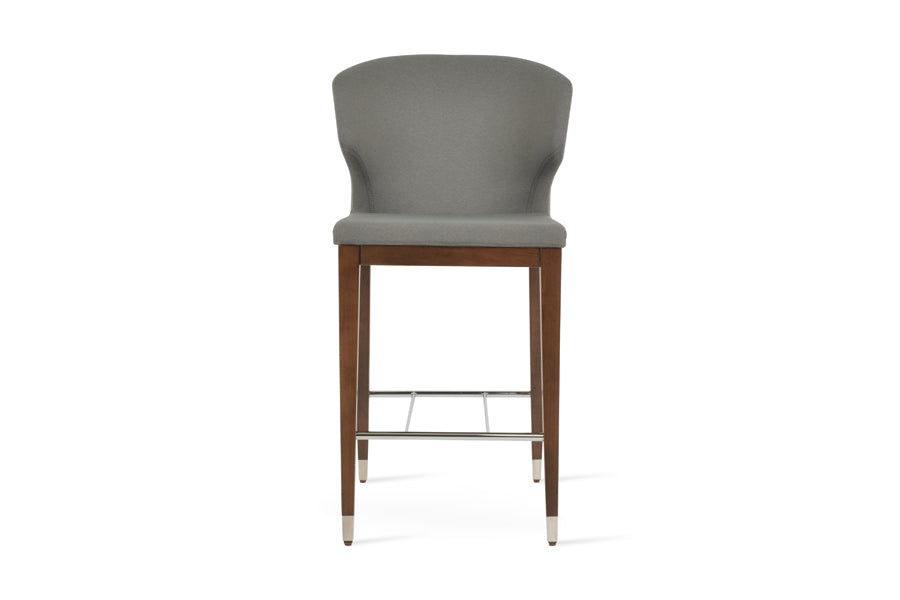 Amed Wood Stool by SohoConcept, showing front view of amed wood stool in beech walnut wood+chrome ring-footrest/camira era grey fabric.