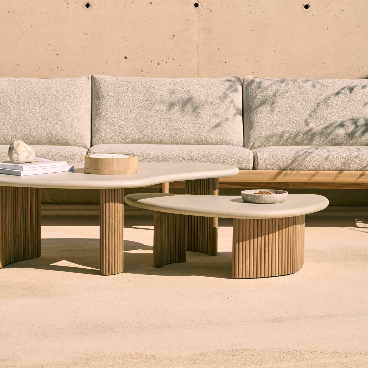 Boomerang Outdoor Coffee Table by Ethnicraft, showing closeup view of boomerang outdoor coffee tables in live shot.