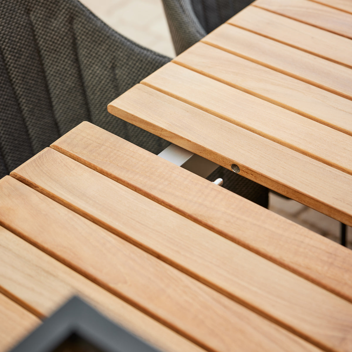 Drop Dining Table with 2pcs Extensions by Cane-Line, showing closeup view of drop dining table with 2pcs extensions in live shot.