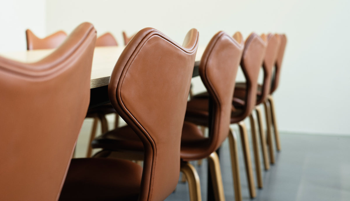 Grand Prix Full Upholstery Wooden Legs Chair by Fritz Hansen, showing closeup view of grand prix full upholstery wooden legs chairs in live shot.