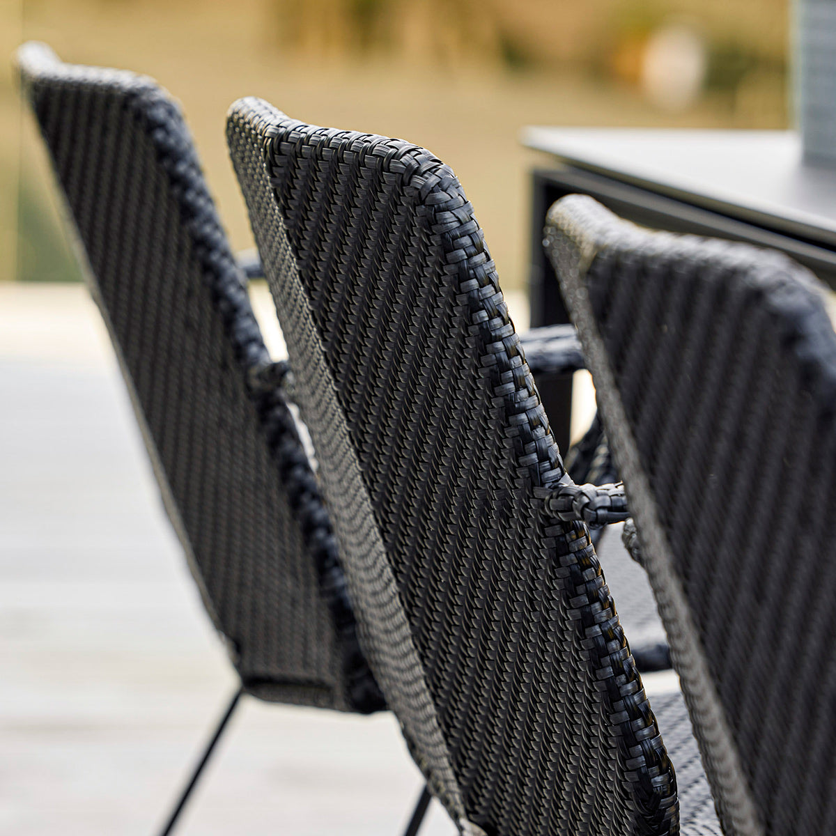 Vision Stackable Armchair by Cane-Line, showing closeup view of vision stackable armchairs in live shot.