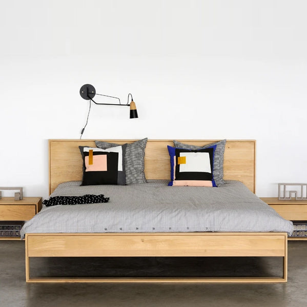 Nordic II Bed with Slats by Ethnicraft, showing front view of nordic oak bed with side table in the live shot.