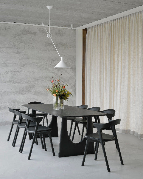Geometric Dining Table by Ethnicraft, showing side view of geometric dining table with chairs in live shot.