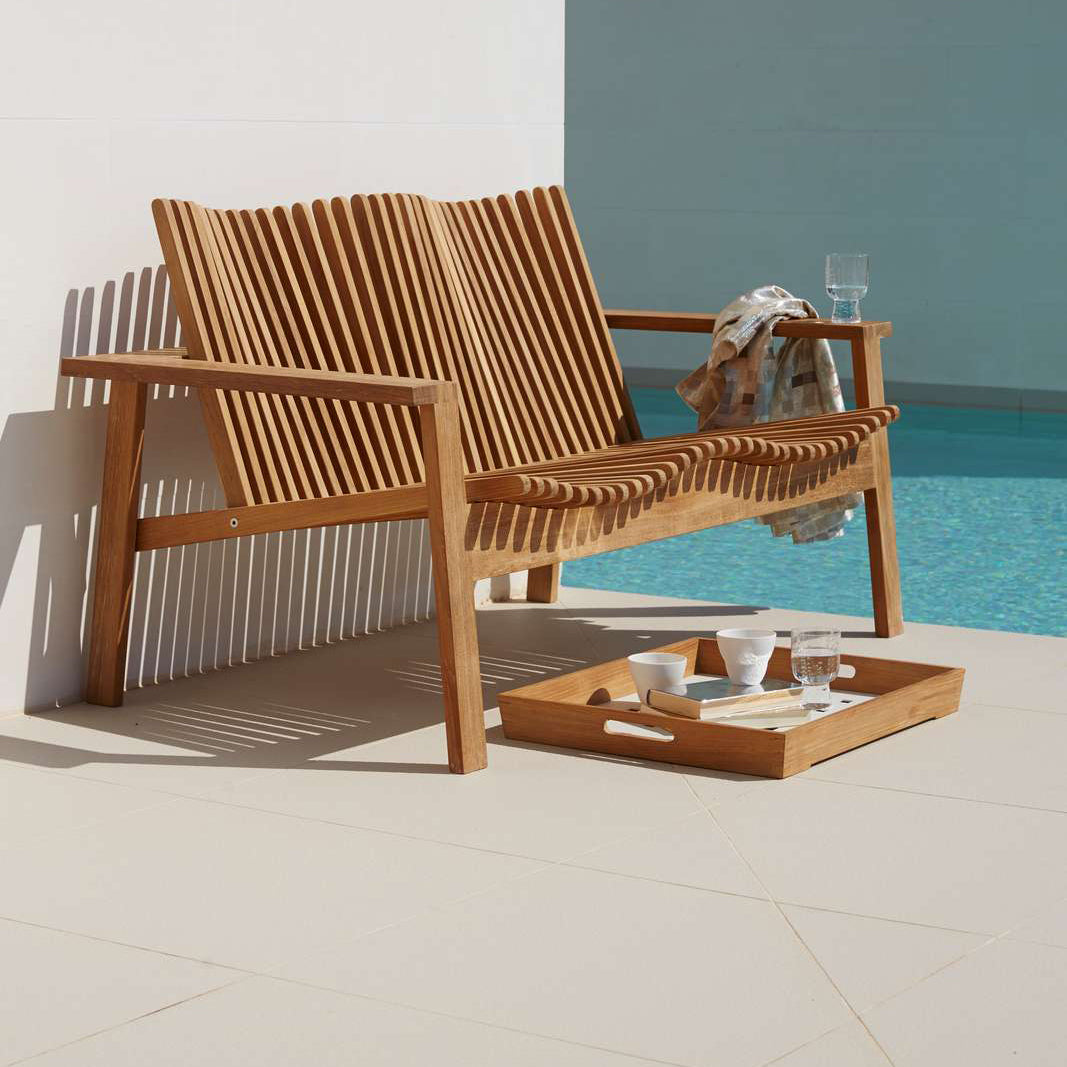 Amaze Stackable 2-Seater Sofa by Cane-Line, showing amaze stackable 2-seater sofa with table tray in live shot.