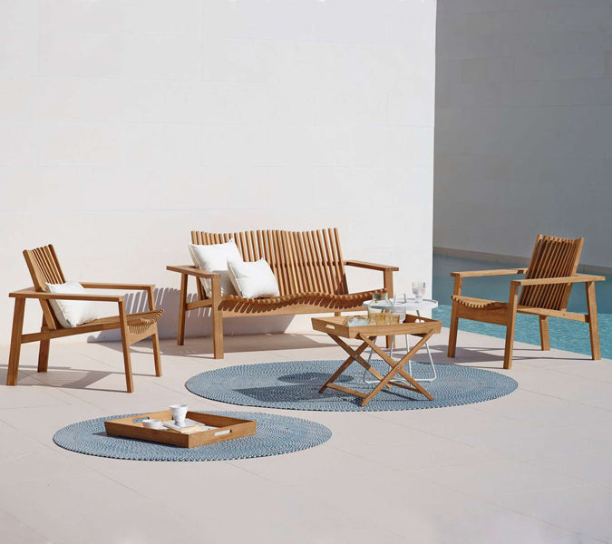 Amaze Stackable 2-Seater Sofa by Cane-Line, showing amaze stackable 2-seater sofa with side table & chairs in live shot.