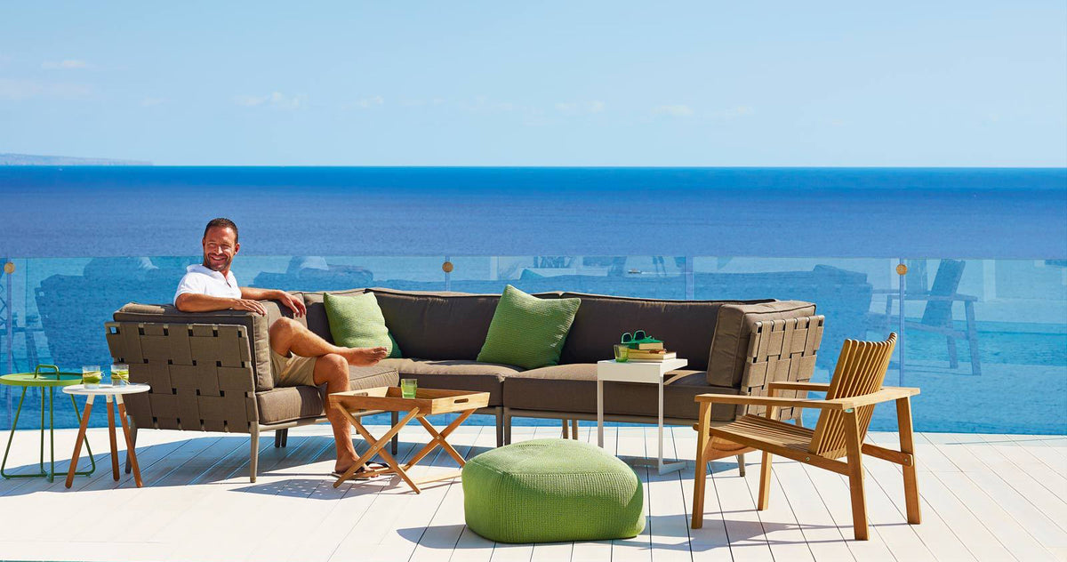 Amaze Stackable Lounge Chair by Cane-Line, showing amaze stackable lounge chair with sectional & side tables in live shot.