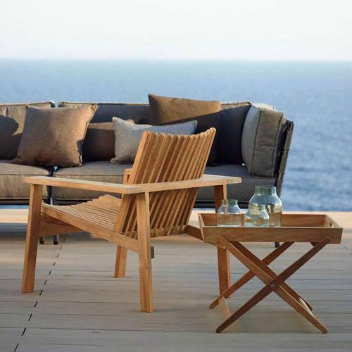 Amaze Stackable Lounge Chair by Cane-Line, showing amaze stackable lounge chair with sectional & side table in live shot.