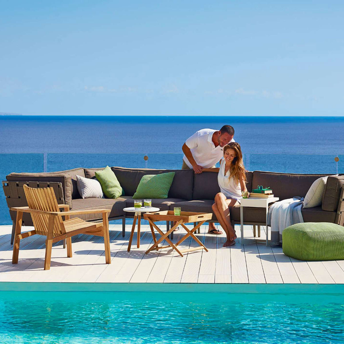 Amaze Stackable Lounge Chair by Cane-Line, showing amaze stackable lounge chair with sectional & side tables in live shot.