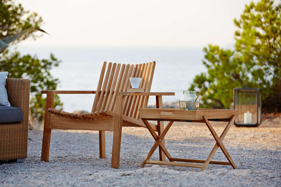 Amaze Stackable Lounge Chair by Cane-Line, showing amaze stackable lounge chair with side table in live shot.