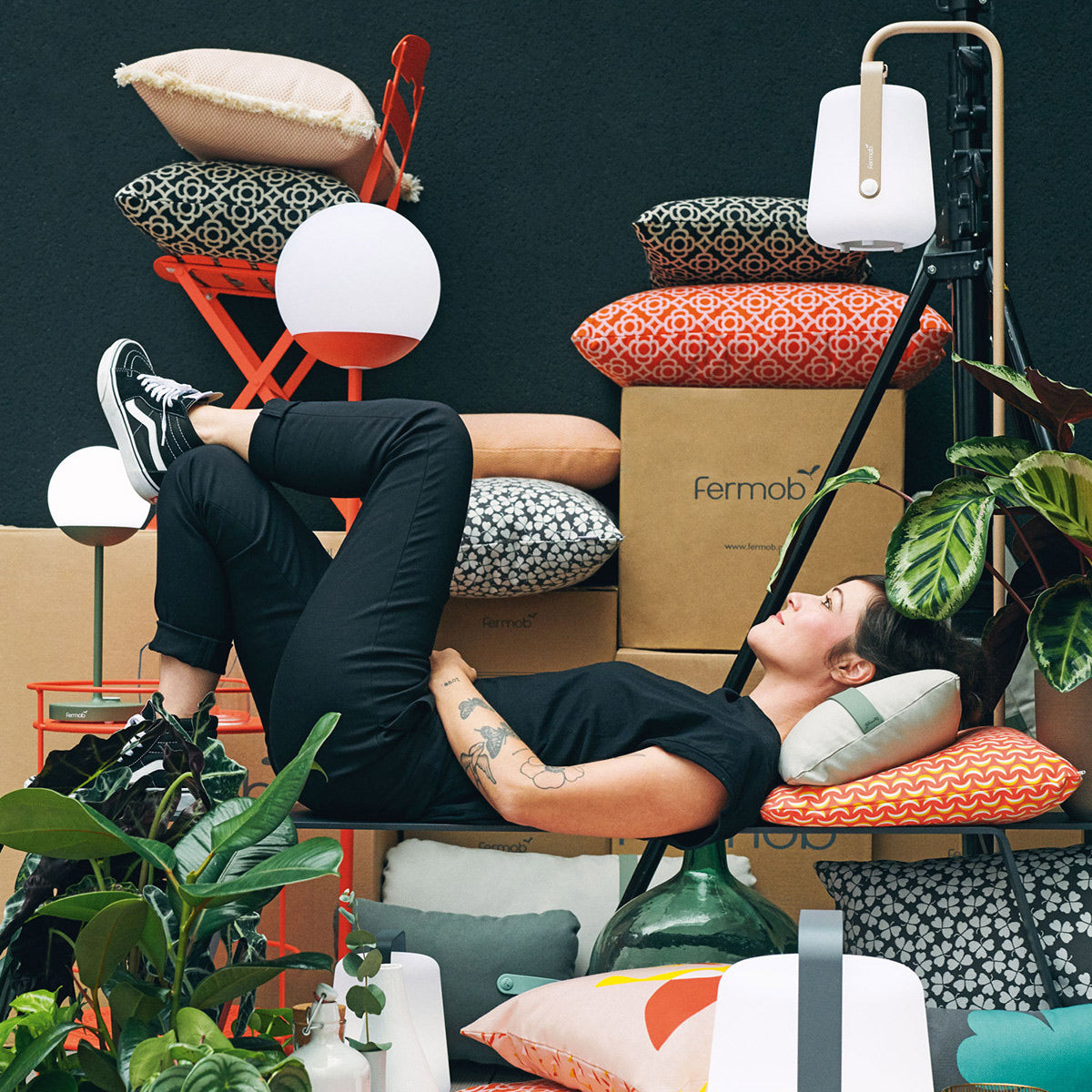 Balad Upright Small Stand by Fermob, showing upright small stands with chair, pillows table in live shot.