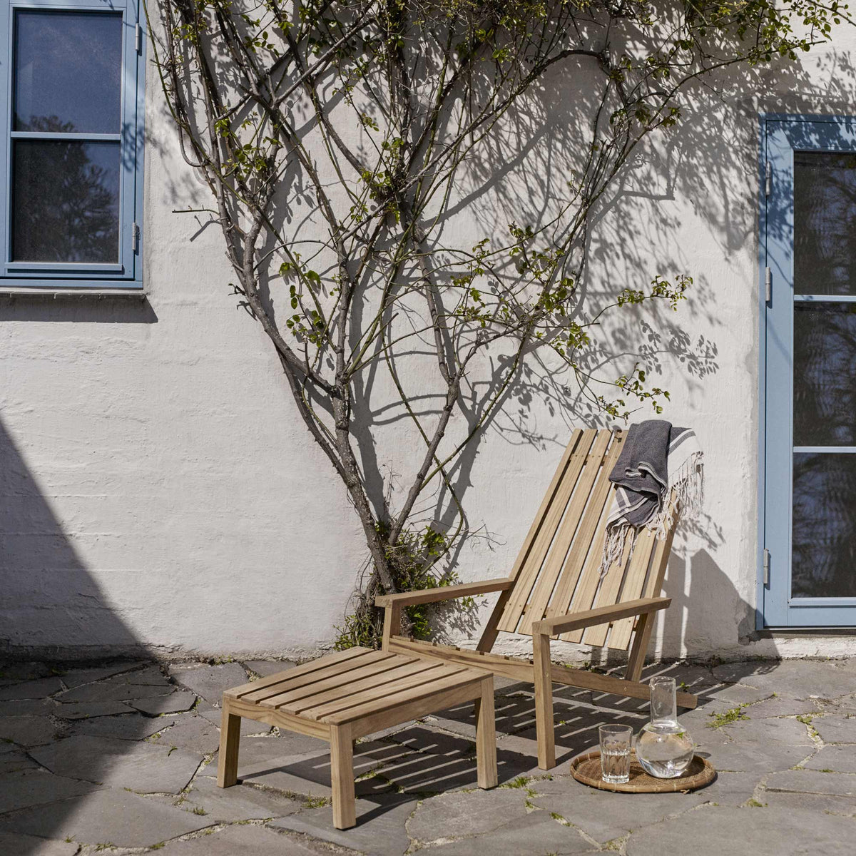 Between Lines Deck Stool by Skagerak, showing between lines deck stool with deck teak chair in live shot.