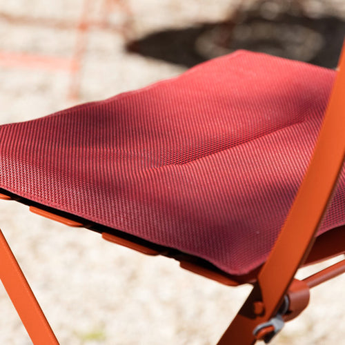 Bistro Outdoor Cushion (Set of 2) by Fermob, showing closeup view of outdoor cushion with chili color on chair in live shot.
