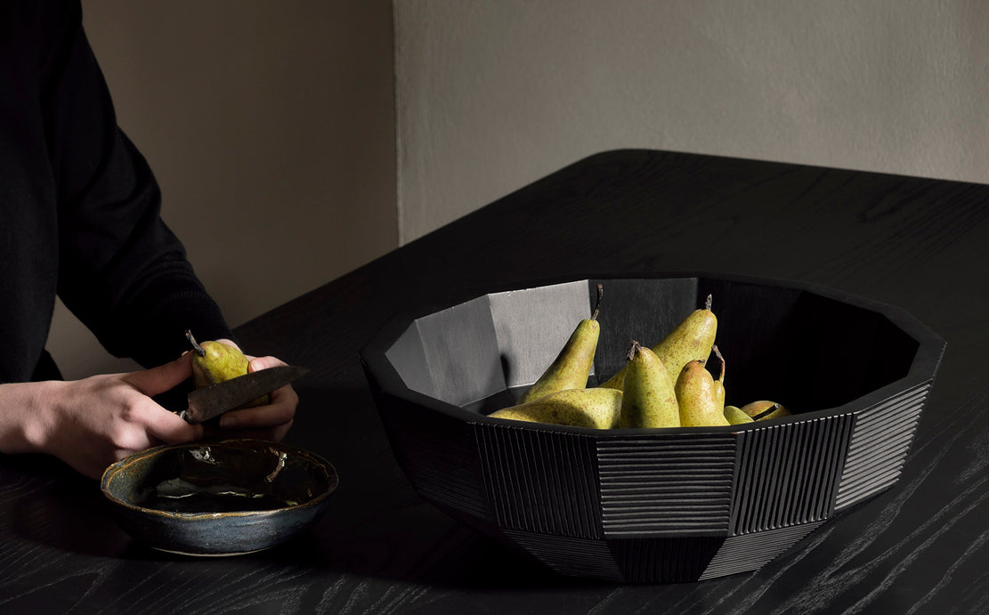 Black Striped Bowl by Ethnicraft, showing front view of striped bowl with fruits in the live shot. 