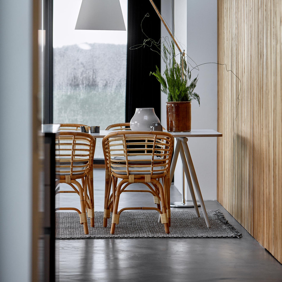 Blend Indoor Armchair by Cane-Line, showing blend indoor armchairs with table in live shot.
