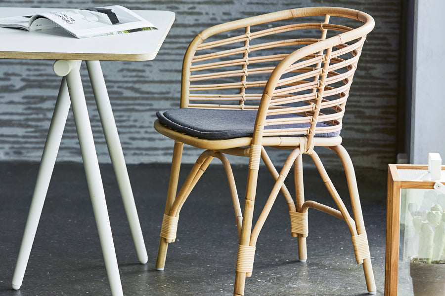 Blend Indoor Armchair by Cane-Line, showing blend indoor armchair with table in live shot.