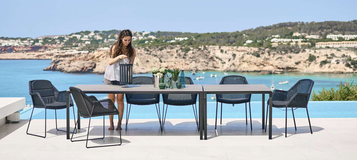 Breeze Dining Chair by Cane-Line, showing breeze dining chairs with table in live shot.