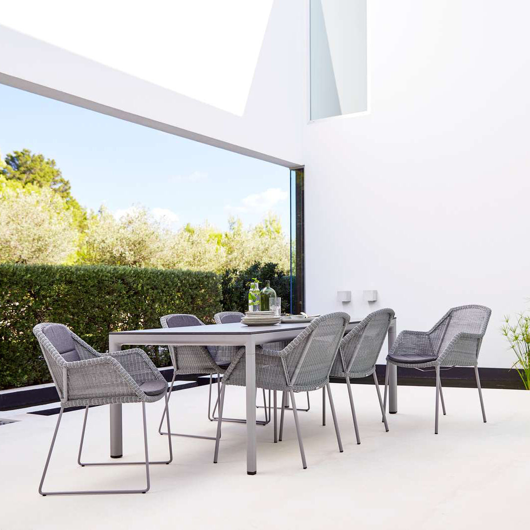 Breeze Dining Chair by Cane-Line, showing breeze dining chairs with table in live shot.