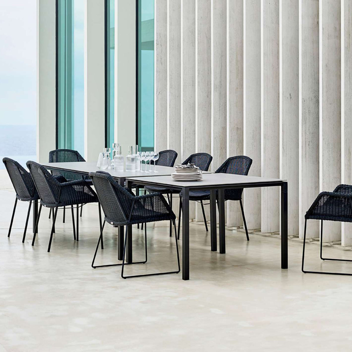 Breeze Dining Chair by Cane-Line, showing breeze dining chairs with table in live shot.