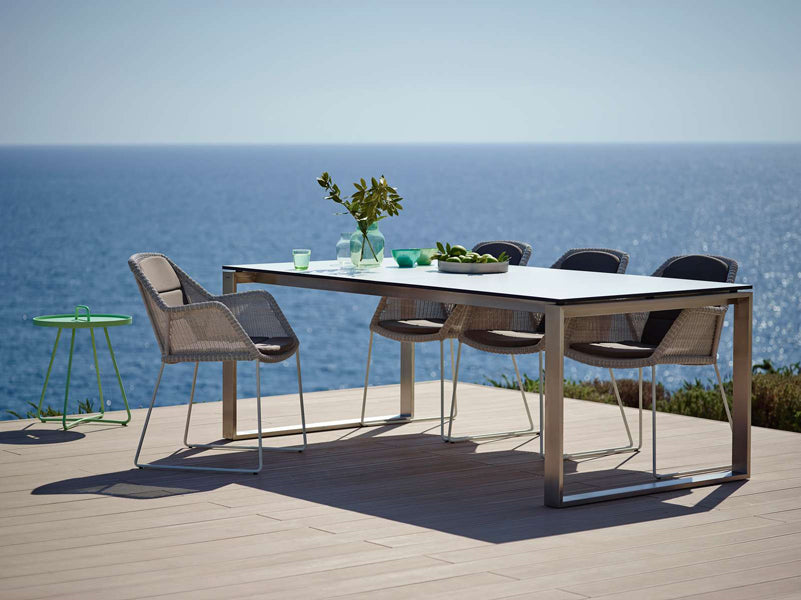 Breeze Dining Chair by Cane-Line, showing breeze dining chairs with table in live shot.