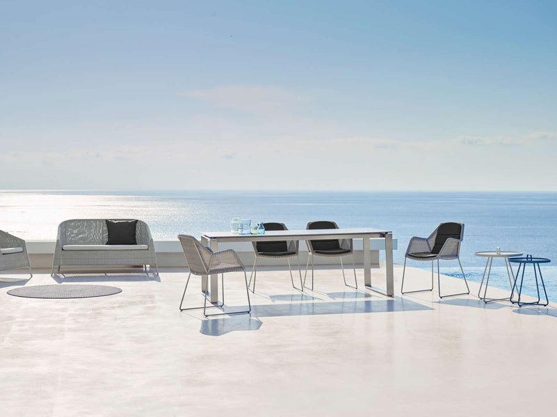 Breeze Dining Chair by Cane-Line, showing breeze dining chairs with table in live shot.