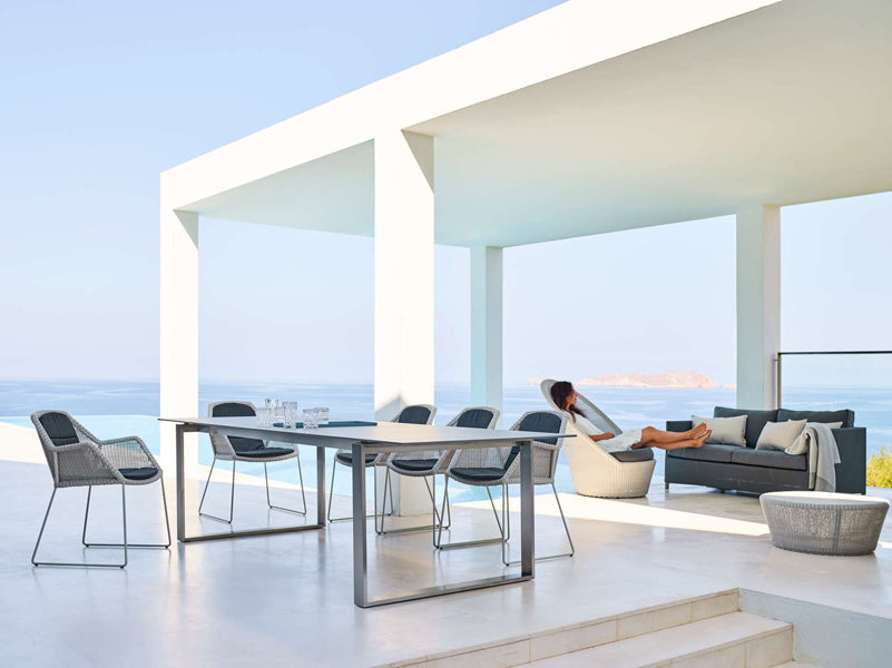 Breeze Dining Chair by Cane-Line, showing breeze dining chairs with table in live shot.