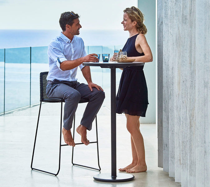 Breeze Stackable Bar Chair by Cane-Line, showing breeze stackable bar chair with table in live shot.