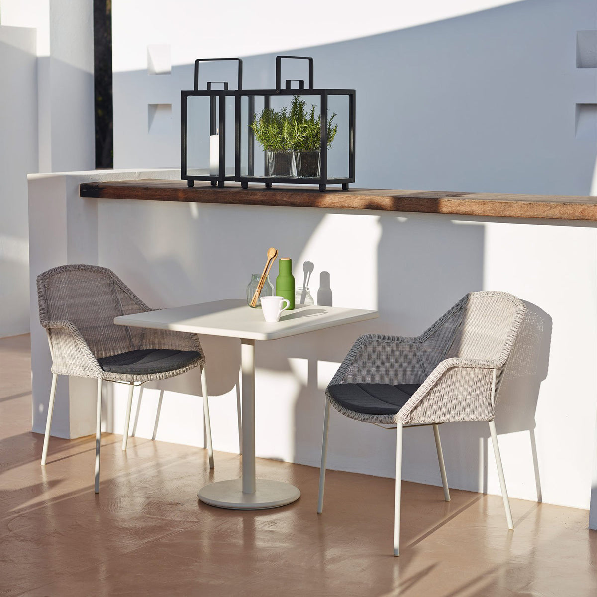 Breeze Stackable Dining Chair by Cane-Line, showing breeze stackable dining chairs with table in live shot.