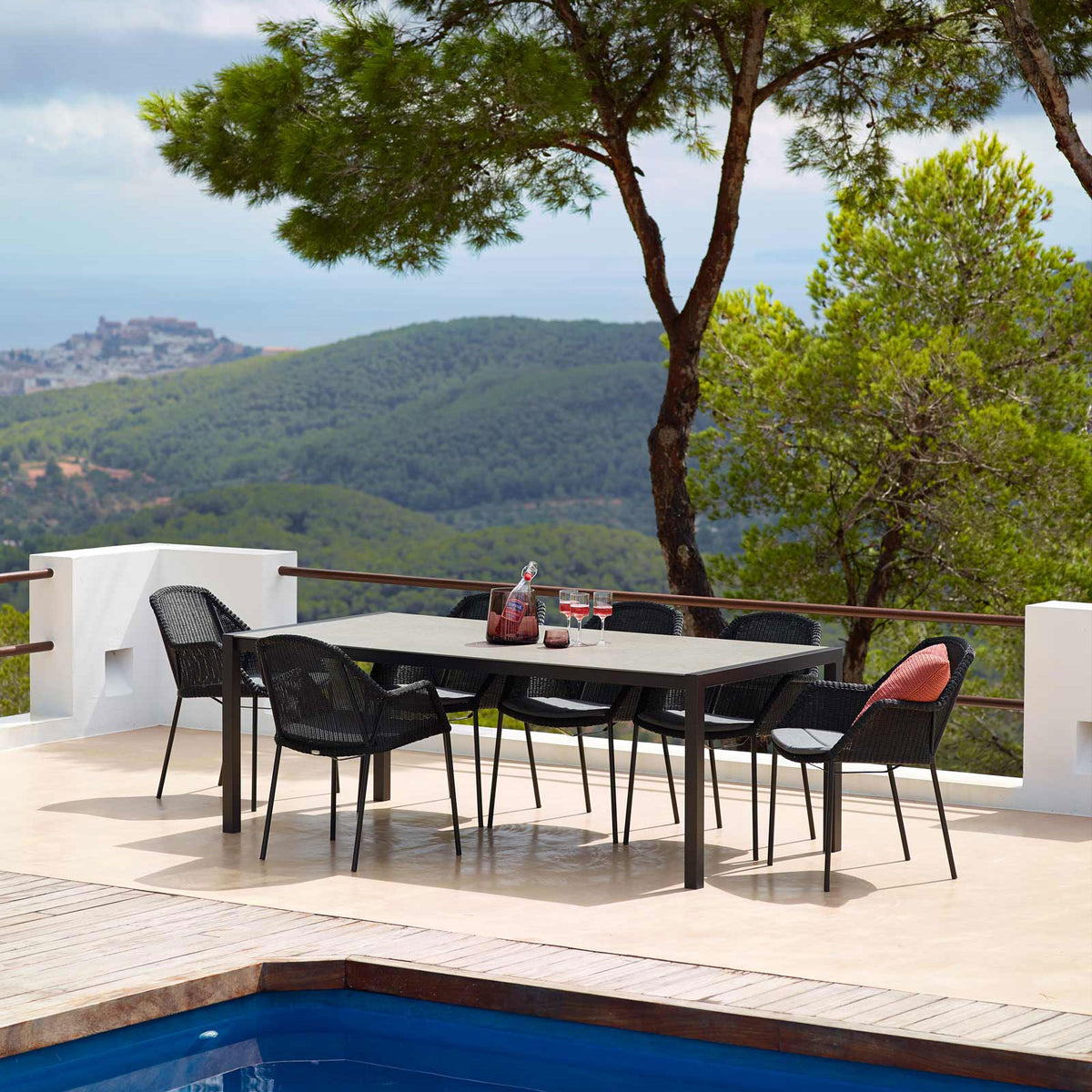 Breeze Stackable Dining Chair by Cane-Line, showing breeze stackable dining chairs with table in live shot.