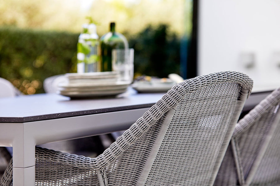 Breeze Stackable Dining Chair by Cane-Line, showing closeup view of breeze stackable dining chair with table in live shot.