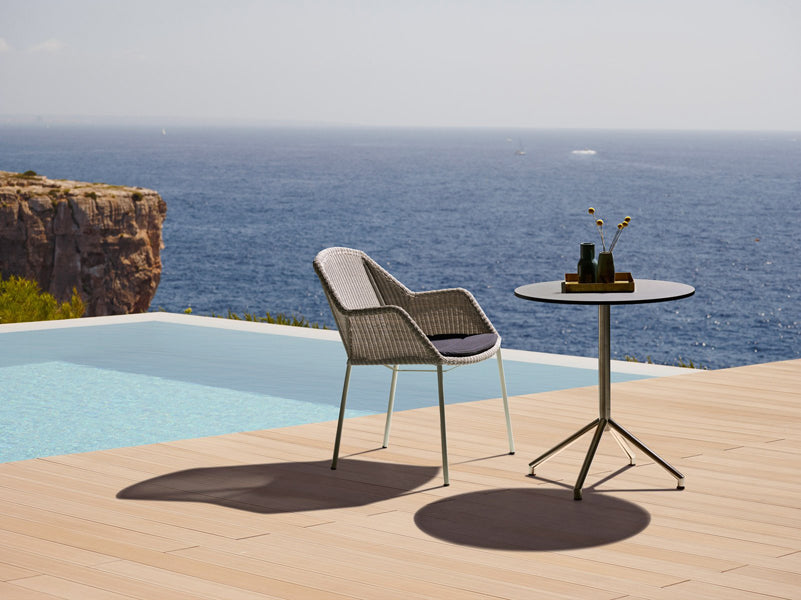 Breeze Stackable Dining Chair by Cane-Line, showing breeze stackable dining chair with table in live shot.