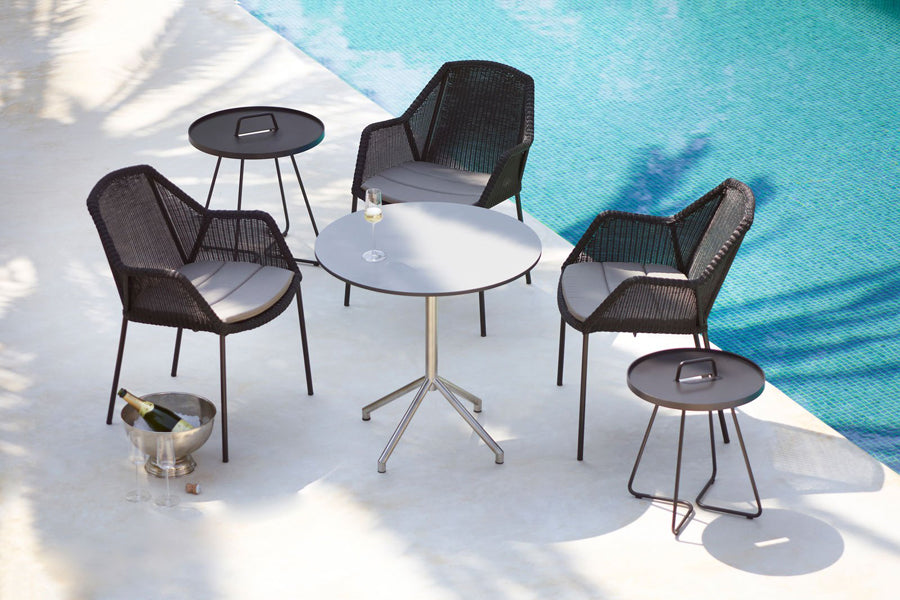 Breeze Stackable Dining Chair by Cane-Line, showing breeze stackable dining chairs with table in live shot.