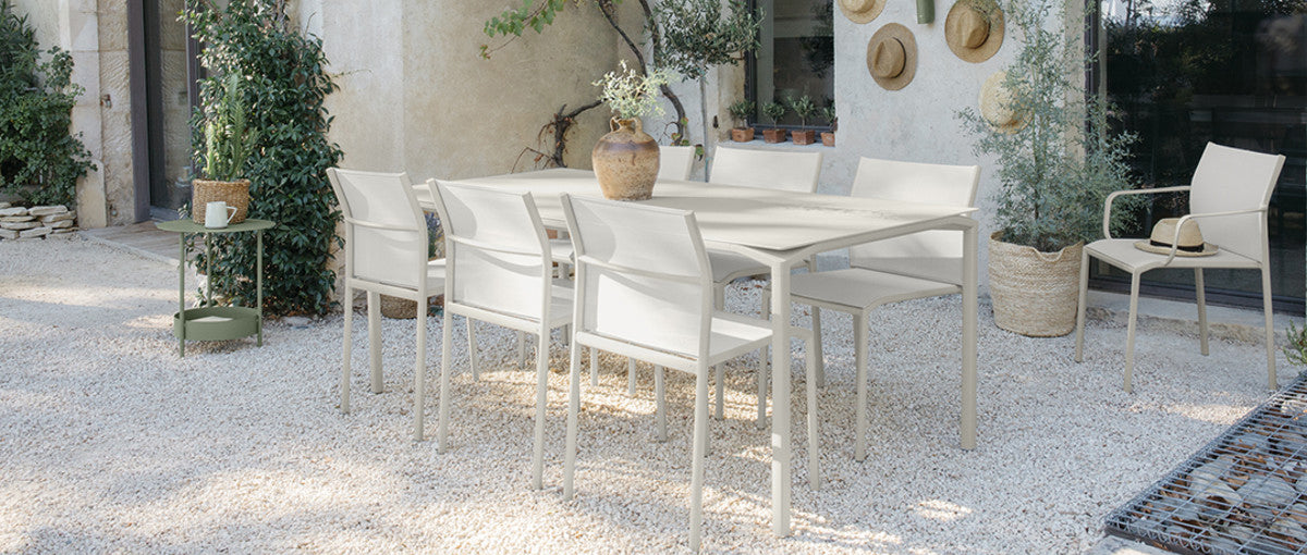 Calvi Dining Table by Fermob, showing of calvi dining table with chairs in live shot.