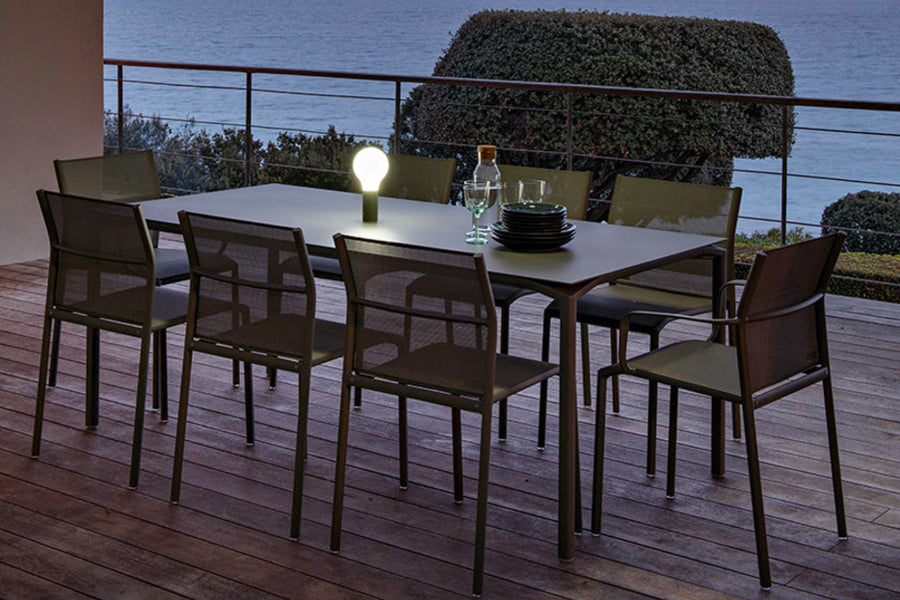 Calvi Dining Table by Fermob, showing of calvi dining table with chairs in live shot.
