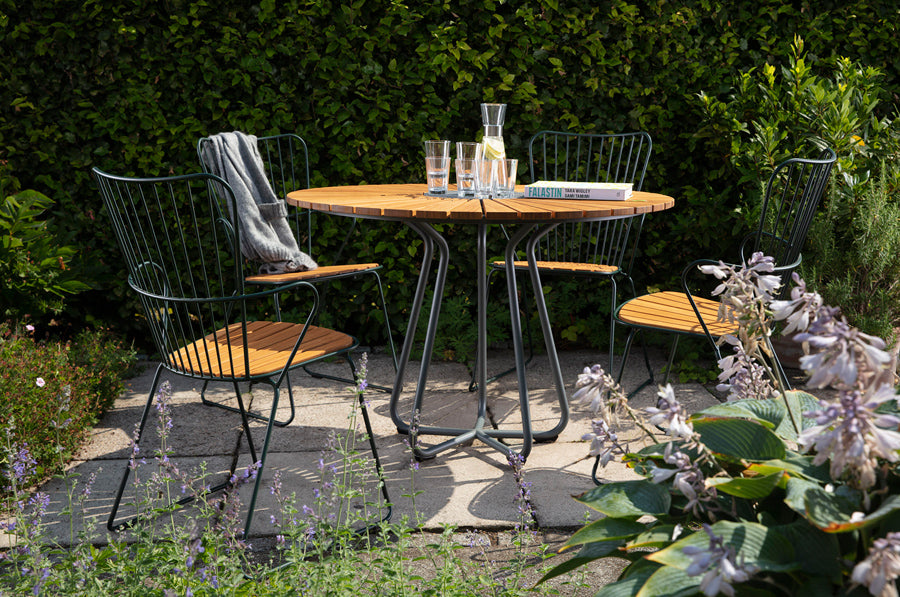 Circle Outdoor Dining Table by Houe, showing circle outdoor dining table with dining chairs in live shot.