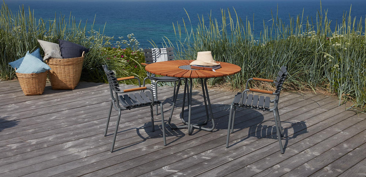 Circle Outdoor Dining Table by Houe, showing circle outdoor dining table with dining chairs in live shot.