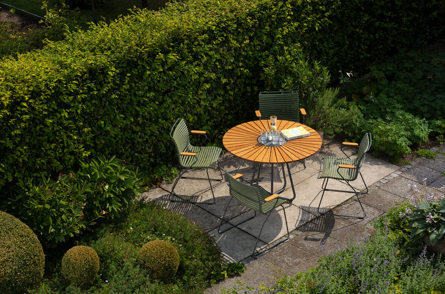 Circle Outdoor Dining Table by Houe, showing circle outdoor dining table with dining chairs in live shot.