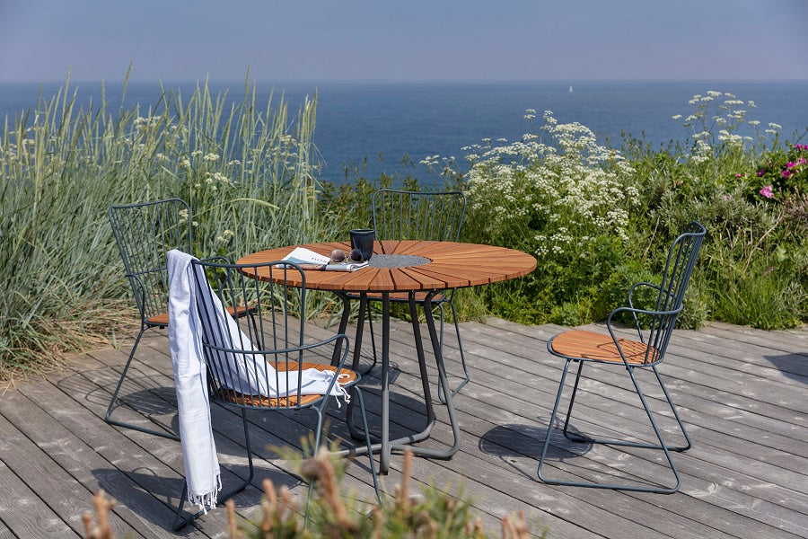 Circle Outdoor Dining Table by Houe, showing circle outdoor dining table with dining chairs in live shot.
