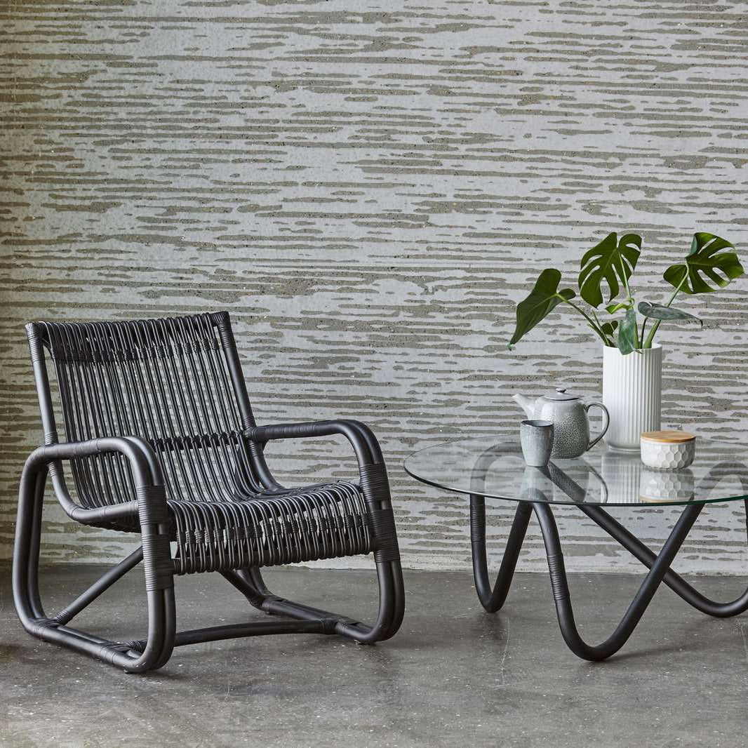 Curve Indoor Lounge Chair by Cane-Line, showing curve indoor lounge chair with table in live shot.