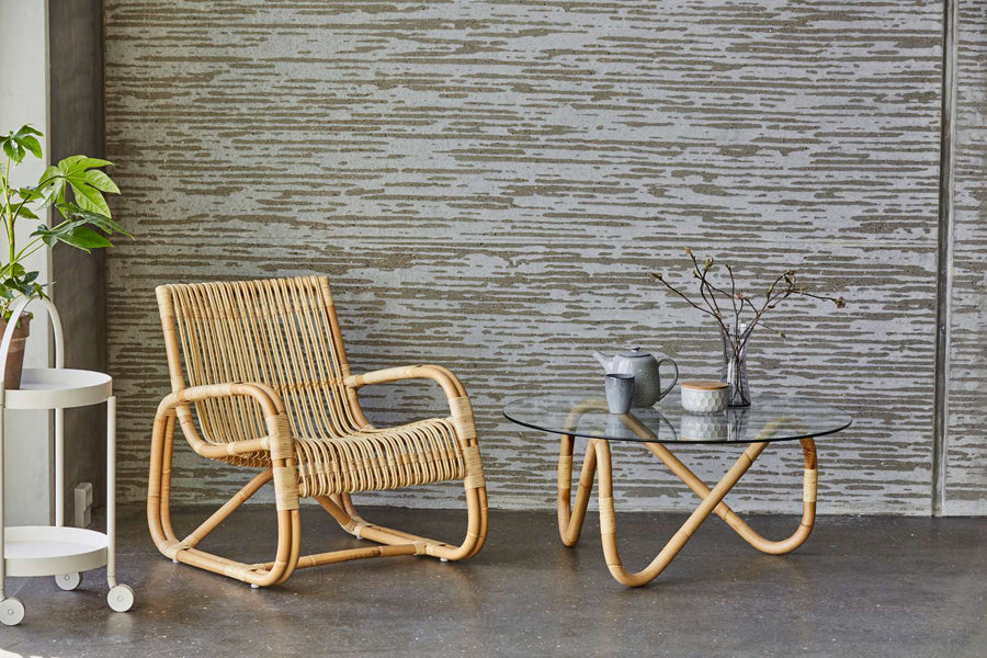 Curve Indoor Lounge Chair by Cane-Line, showing curve indoor lounge chair with table in live shot.