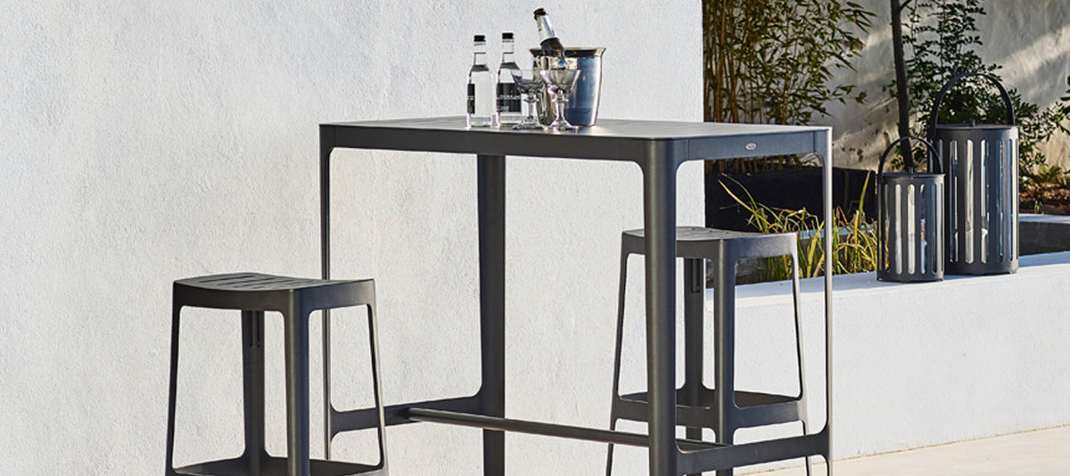 Cut High Bar Table by Cane-Line, showing cut high bar table with stools in live shot.