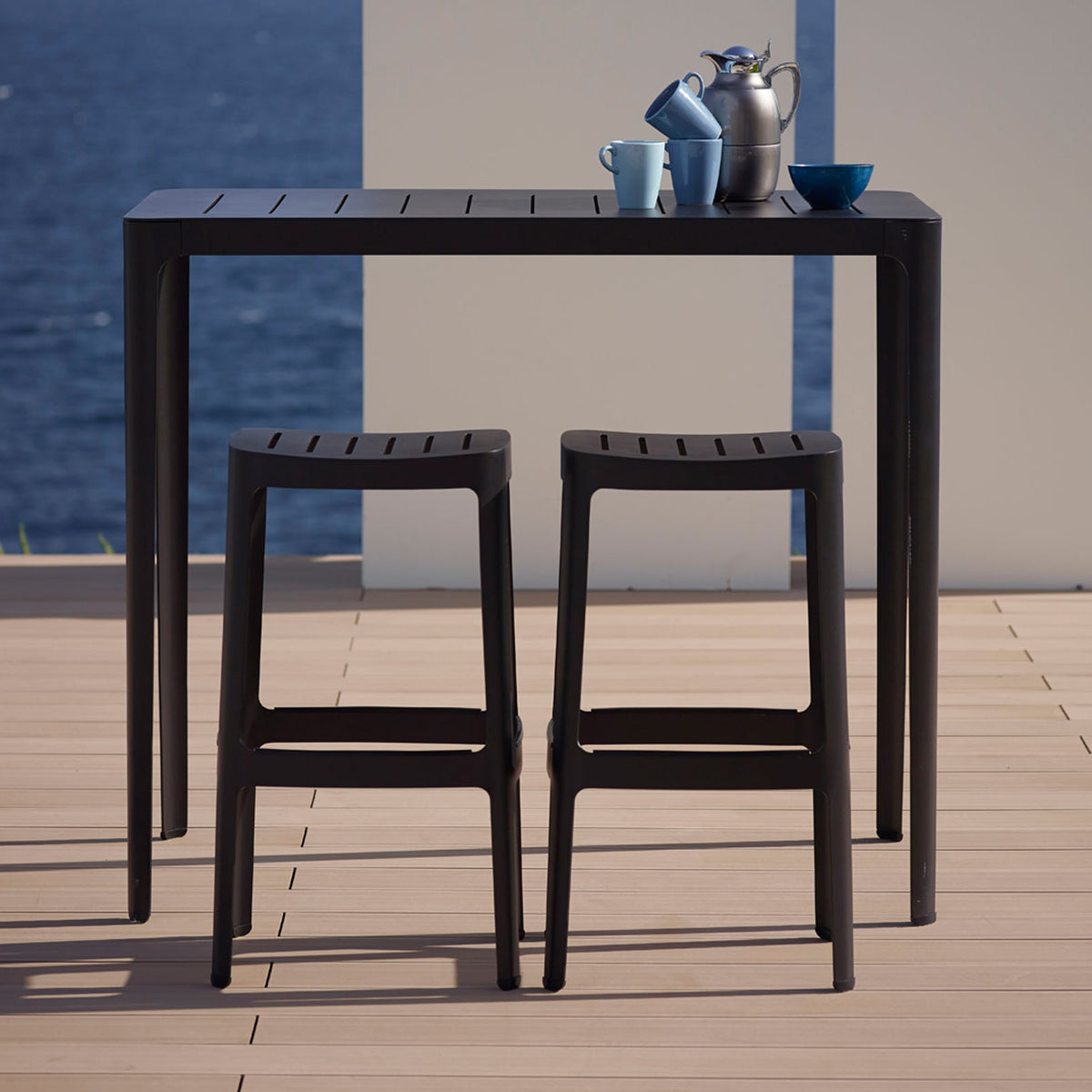 Cut High Bar Table by Cane-Line, showing cut high bar table with stools in live shot.