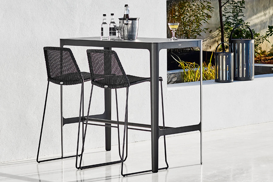 Cut High Bar Table by Cane-Line, showing cut high bar table with high chairs in live shot.