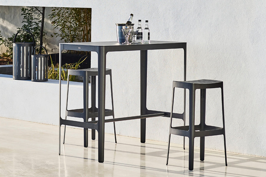 Cut High Bar Table by Cane-Line, showing cut high bar table with stools in live shot.