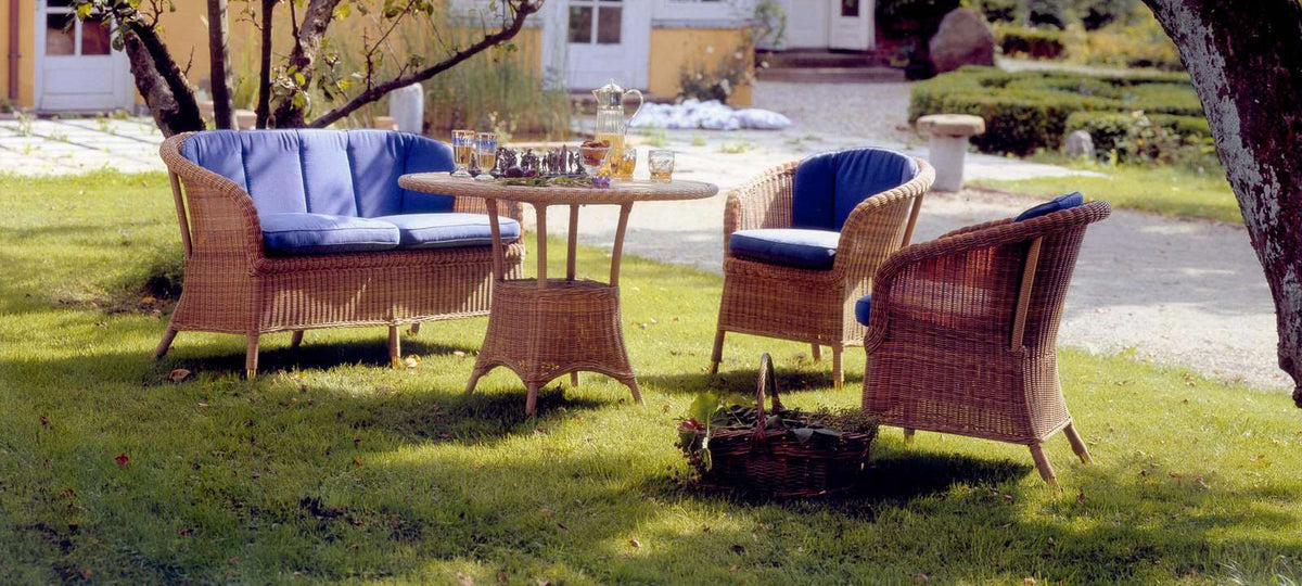 Derby Arm Chair by Cane-Line, showing derby arm chairs with table & sofa in live shot.