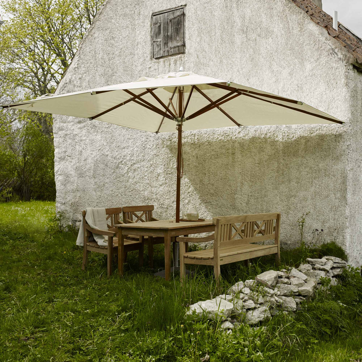 Drachmann Bench by Skagerak, showing drachmann benches with umbrella and table in live shot.