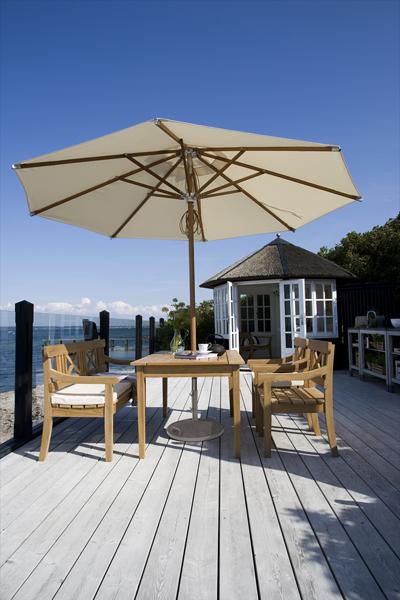 Drachmann Teak Chair by Skagerak, showing drachmann teak chairs with table, bench and umbrella in live shot.